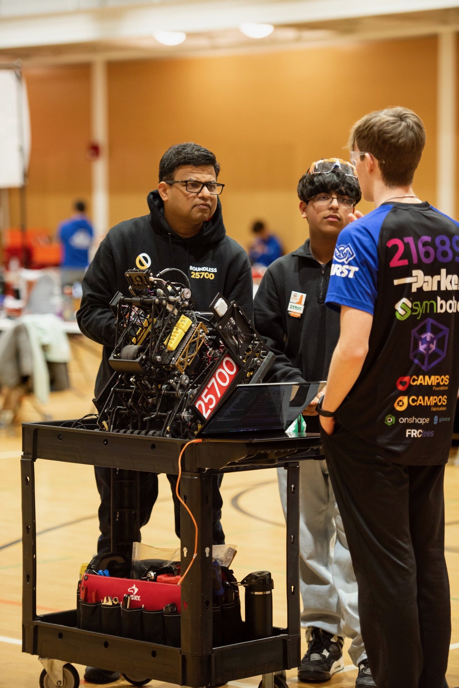 Drive team talking in the pits with the robot on a cart